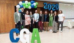 The graduates stand in front of large CGA letters.
