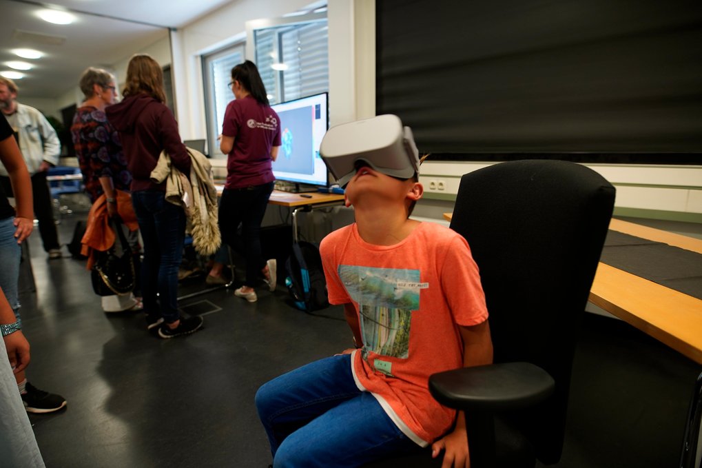 A boy wearing VR goggles looks up into the air.