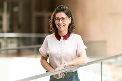 Woman in a white blouse with a red collar standing by a railing.
